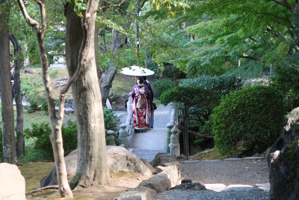 Japanese garden in Ryogoku with woman in kimono crossing small stone bridge Tokyo