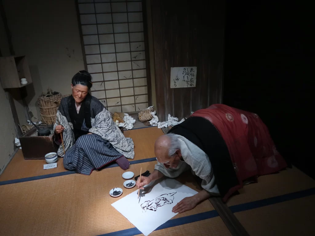 Recreation of Hokusai drawing scene inside museum showing traditional Japanese artist at work